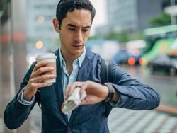 man-looking at watch with cup of coffee
